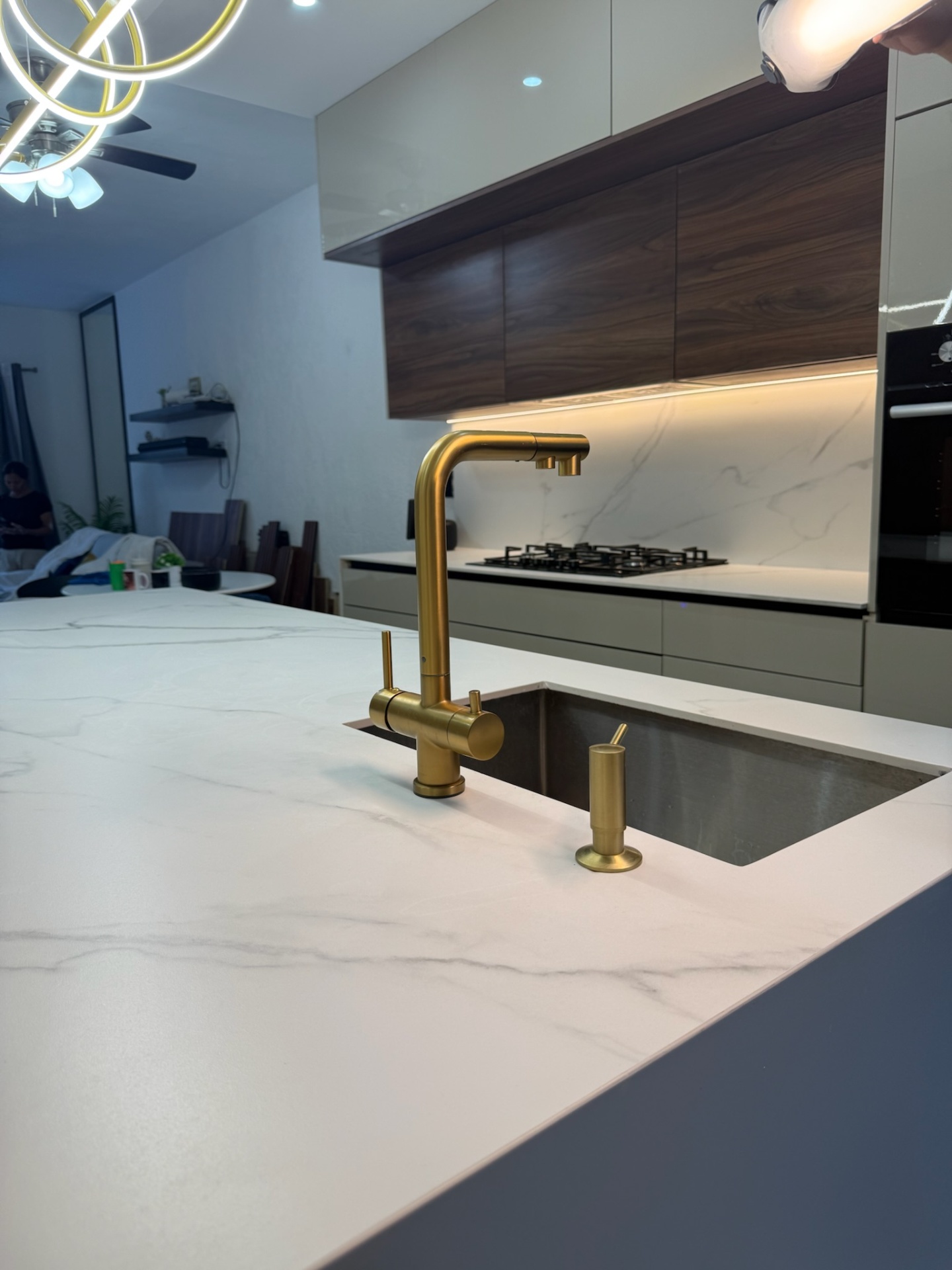 Isla de cocina en Griego White con cascadas laterales y grifería en tono dorado