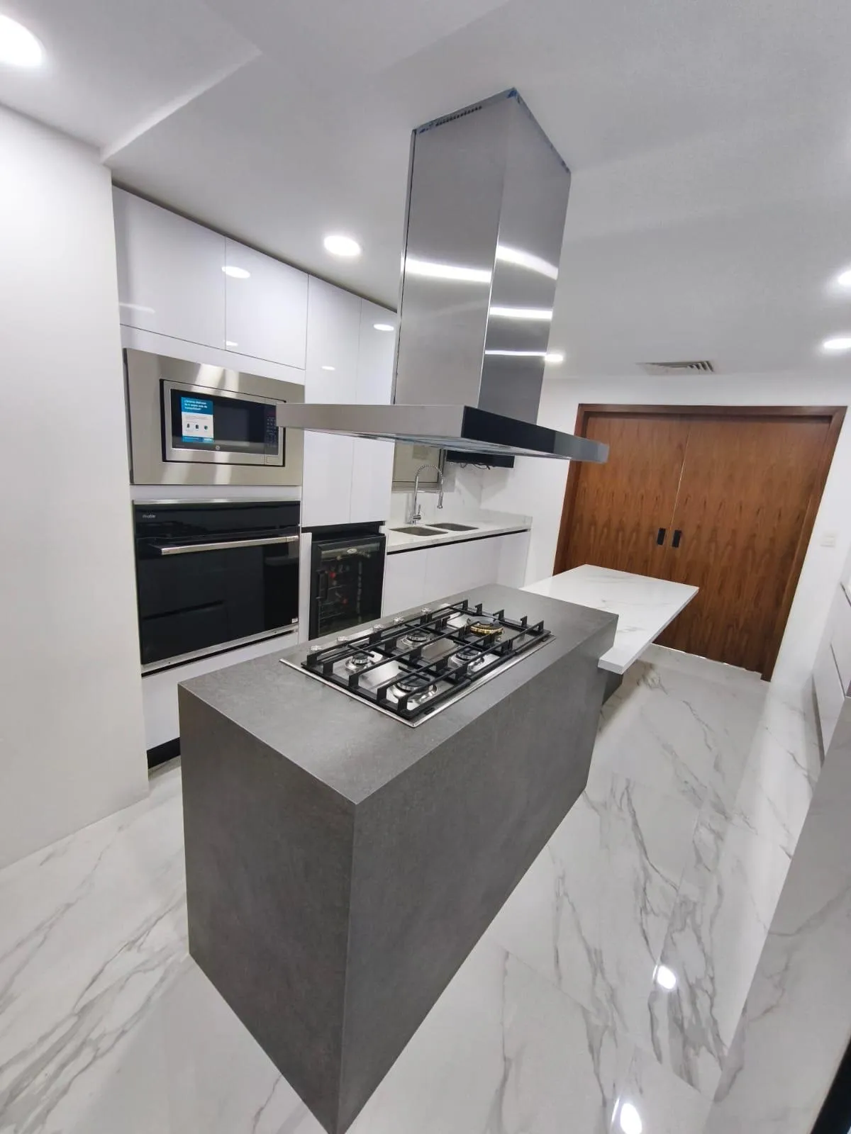 Vista de la isla de cocina con campana de acero inoxidable y cubierta de piedra sinterizada