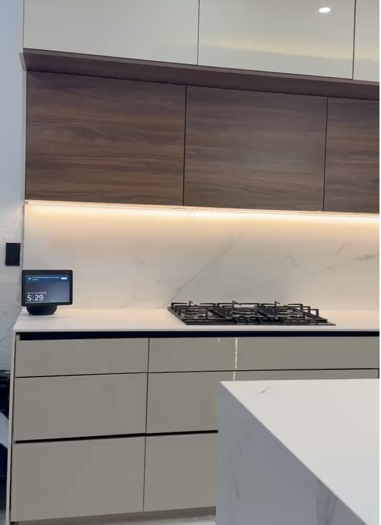 Gabinetes superiores con iluminación LED indirecta sobre la cubierta y backsplash en Griego White