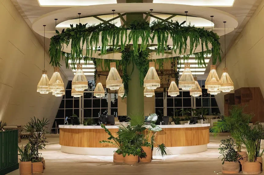Lobby del Hotel Sirenis con recepción circular de madera y vegetación colgante