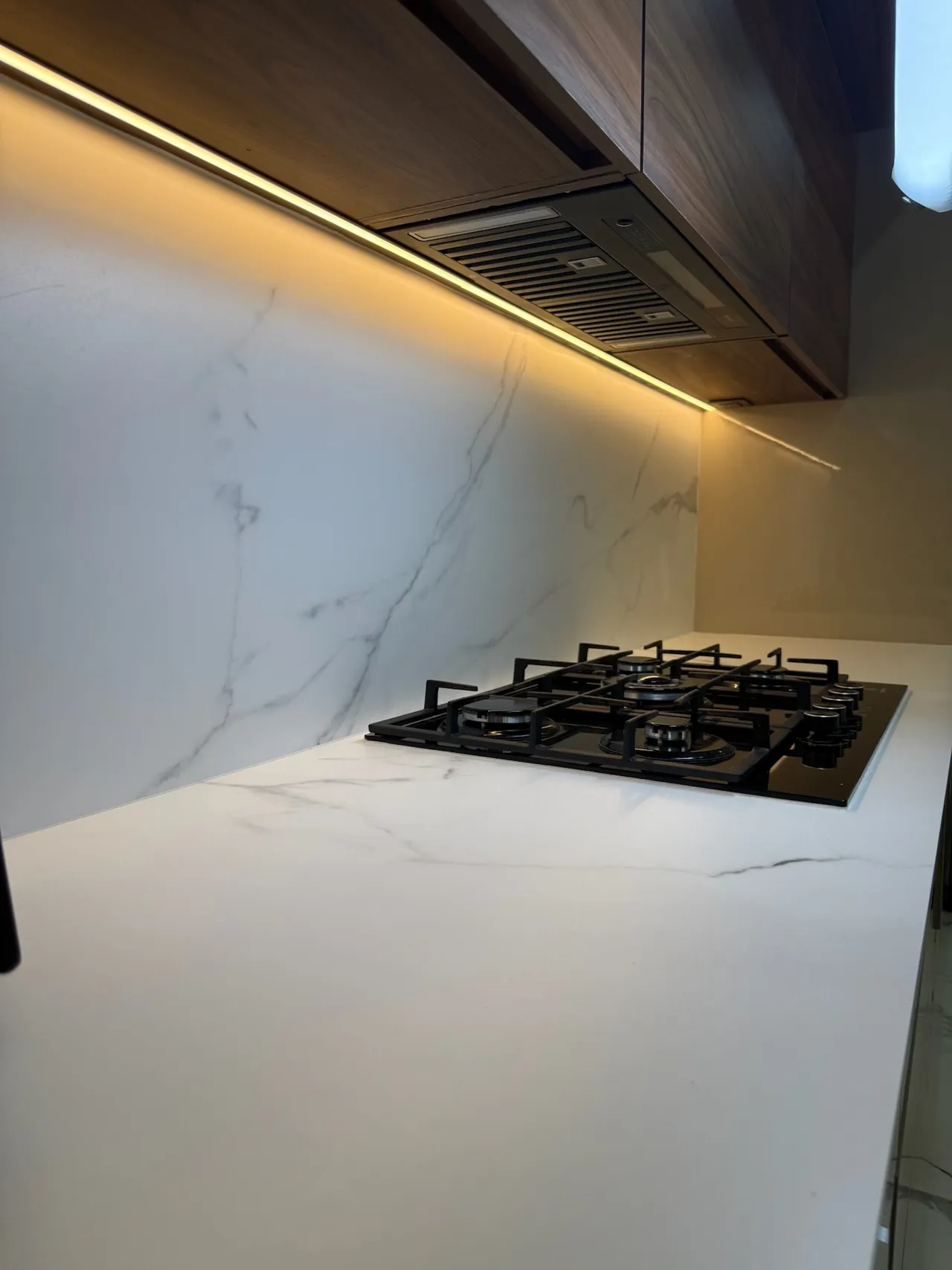 Zona de cocción con backsplash continuo en Griego White y luz cálida