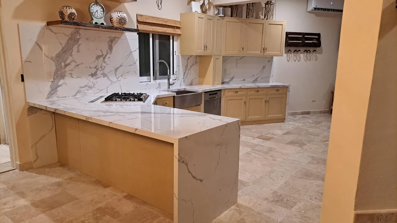 Isla cascada en piedra sinterizada integrada al diseño de la cocina remodelada